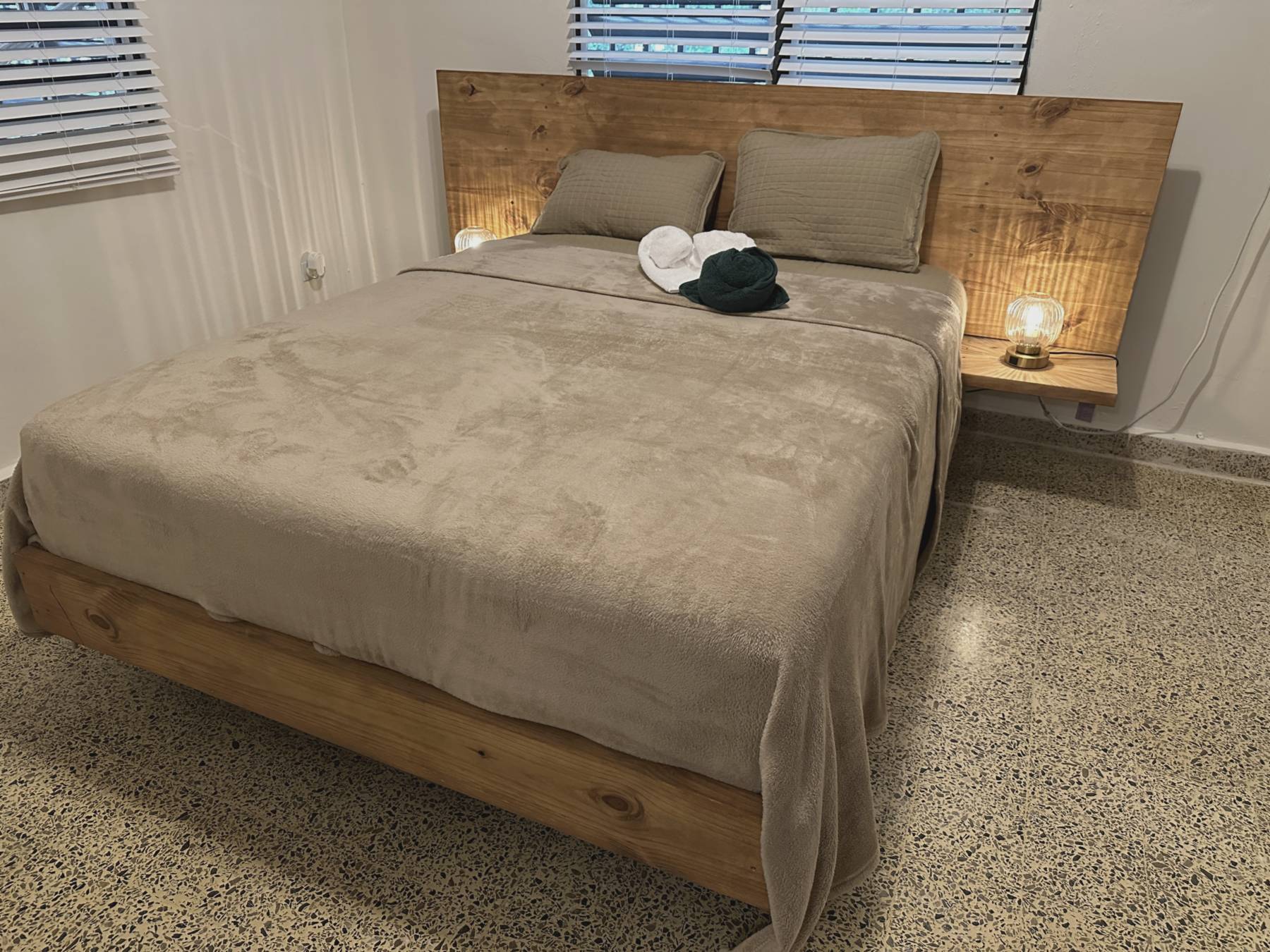 Casa Yuké bedroom with custom wood bed frame and warm reading lamps
